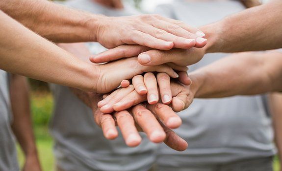 Group of people in a circle putting their hands together in the center