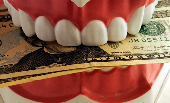 a plastic model of teeth biting down on money