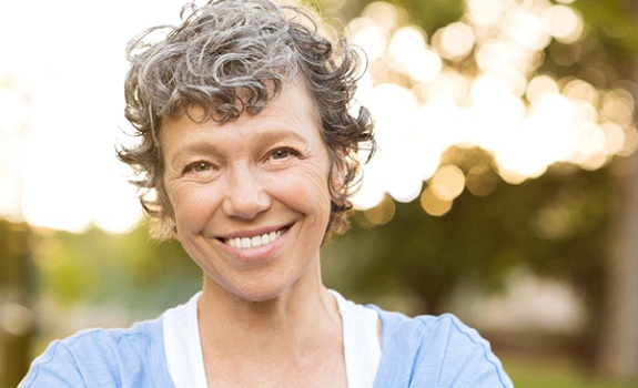 Woman with short curly hair smiling outside