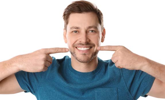 Man with dental bridge in Lakewood Dallas pointing to his smile