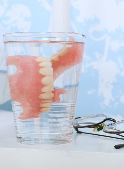 Dentures in Lakewood in glass of water on bedside table