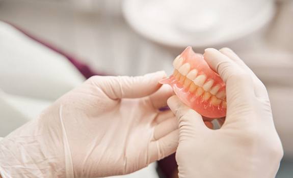 a dentist holding onto a pair of dentures