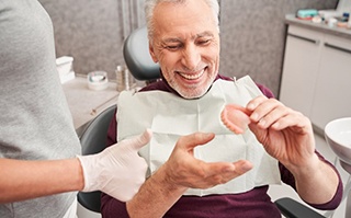 a patient smiling while receiving his brand-new dentures