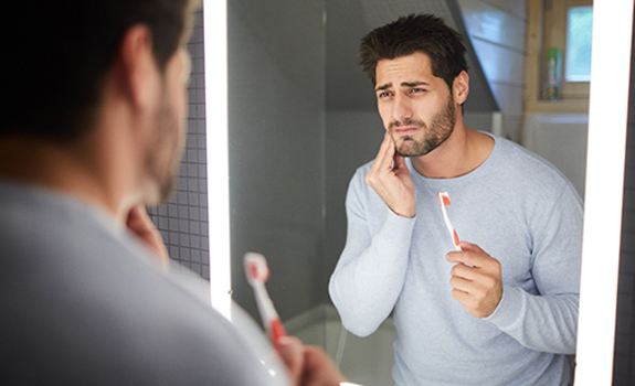 Man with dental emergency in Lakewood, Dallas holding a toothbrush