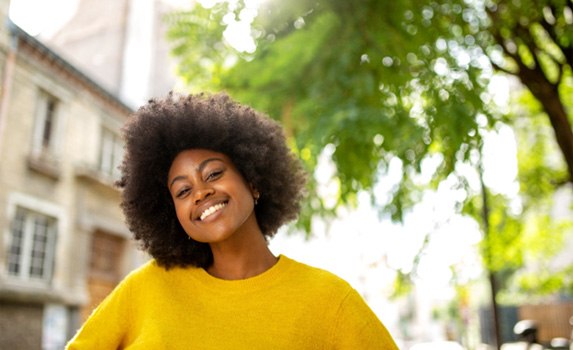 Woman in yellow shirt outside and smiling