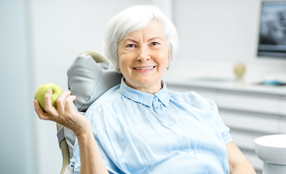 senior woman at the dentist holding an apple