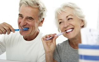 senior man and woman brushing their teeth