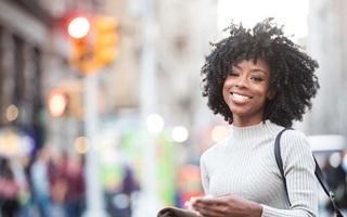 Smiling woman in sweater walking down city streets