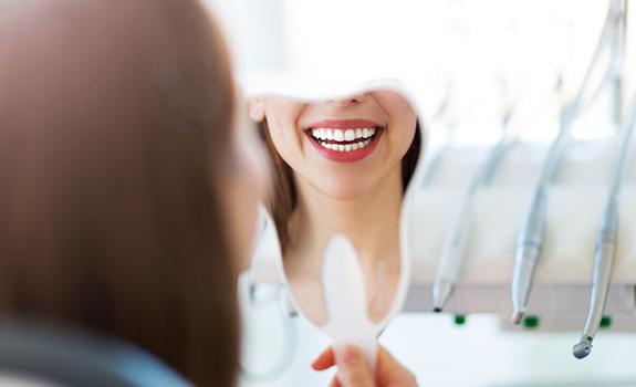 Woman looking at smile after dental implant tooth replacement