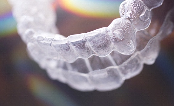 An Invisalign aligner tray sitting on a mirrored surface