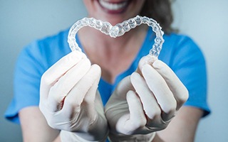 dental hygienist holding two aligners in the shape of a heart 