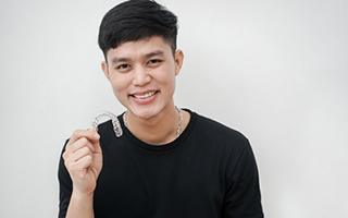 young man holding a clear aligner 