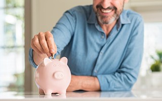 man putting change into a pink piggy bank 