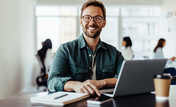 Man smiling while working on laptop in office