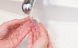 Patient rinsing clear aligners in sink