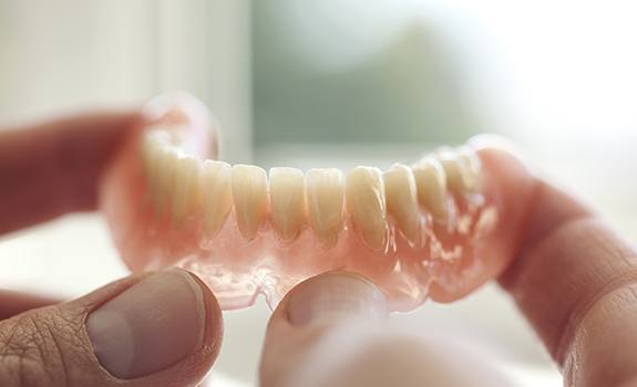 Hand holding a full denture