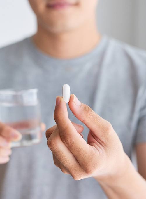 Man holding pill before seeing his sedation dentist 