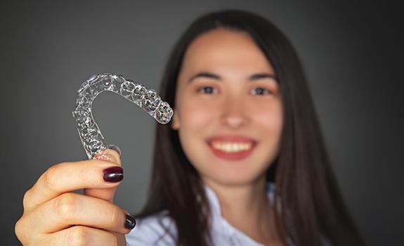 Woman holding up an Invisalign tray