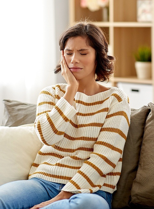 Woman in need of root canal therapy holding cheek