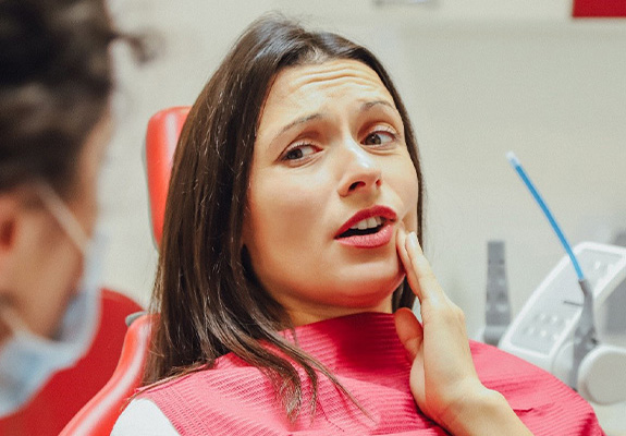 Woman holding cheek during root canal treatment appointment