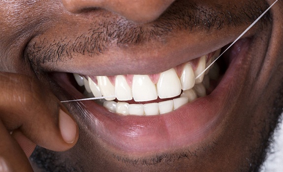 man flossing teeth after getting teeth whitening in Dallas