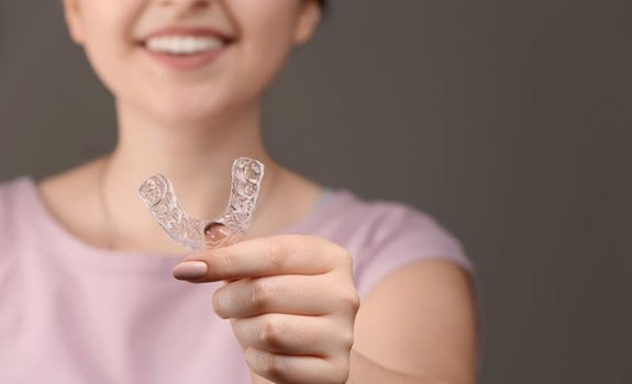 Smiling woman holding an occlusal splint