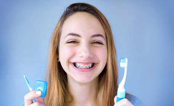 Woman with braces holding a toothbrush and floss