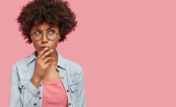 Woman on pink background wondering about veneers in Lakewood 