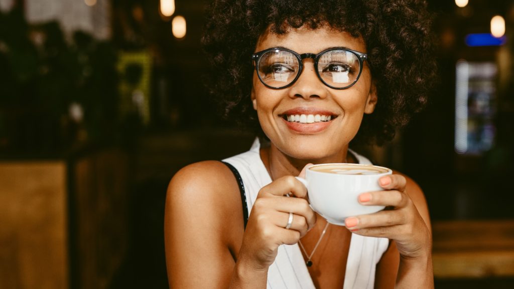 Smiling woman with glasses enjoying cup of coffee