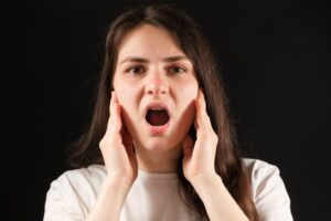 Young woman holding her jaw in pain.