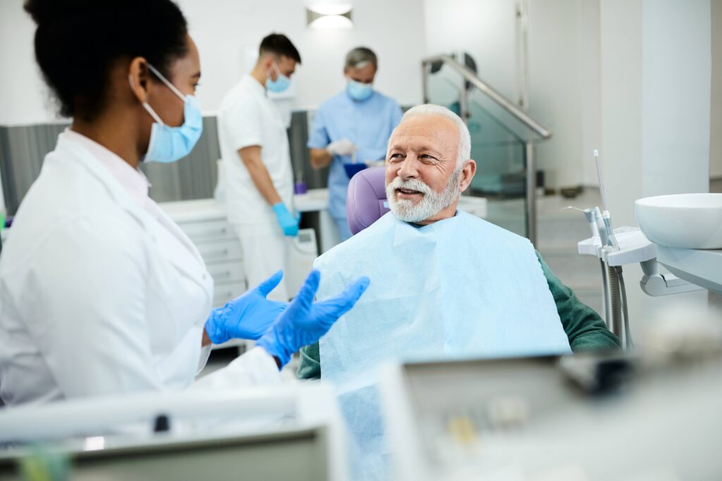 Dentist talking to smiling patient in treatment room