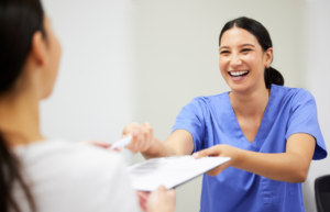 a woman in scrubs handing a patient paperwork